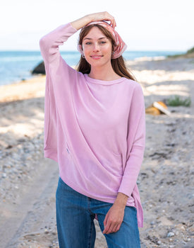 Female wearing a pink sweater standing on the beach