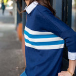 Woman wearing a blue and white striped sweater on a city street.