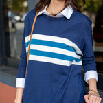 Woman wearing a blue sweater with white and blue stripes, standing outdoors.