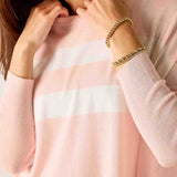Close-up of a person wearing a pink sweater with a white stripe, holding their collar.