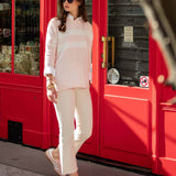 Woman in a light pink outfit walking past a red door