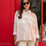 Woman wearing a light pink blouse with a red door in the background