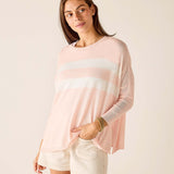 Woman wearing a light pink long-sleeve top with a white stripe and white shorts on a beige background