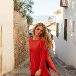 female wearing red sweater with dark jeans spinning in the streets of the country side of spain