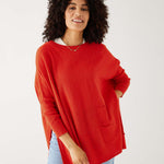 female wearing red sweater with light wash jeans on a white background