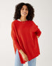 female wearing red sweater with light wash jeans on a white background