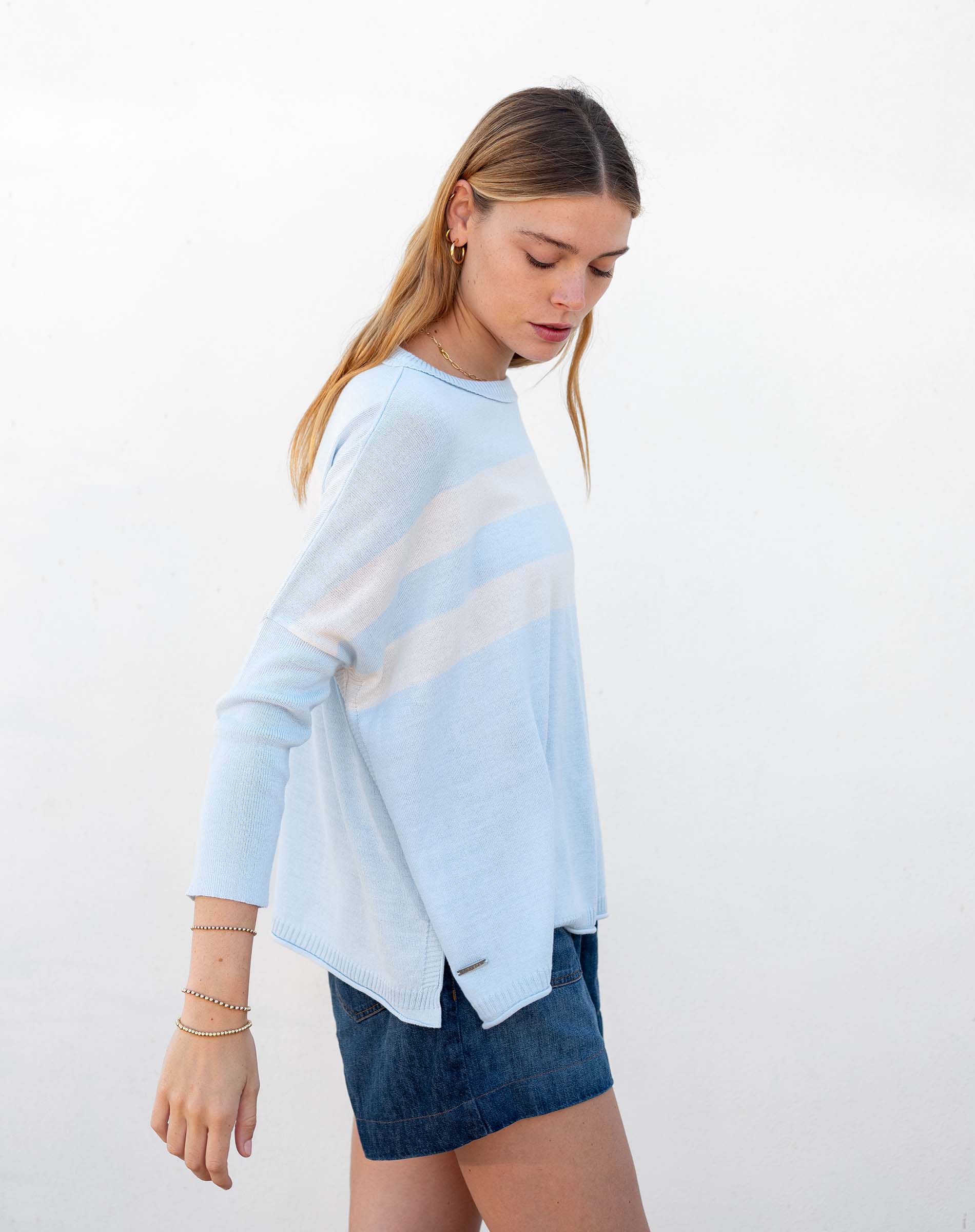 Woman wearing a light blue sweater with a white stripe on a white background