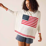 Woman wearing a white sweater with an American flag design on a plain background