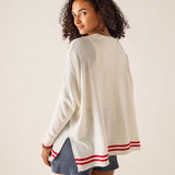 Woman wearing a white sweater with red stripes on a plain background