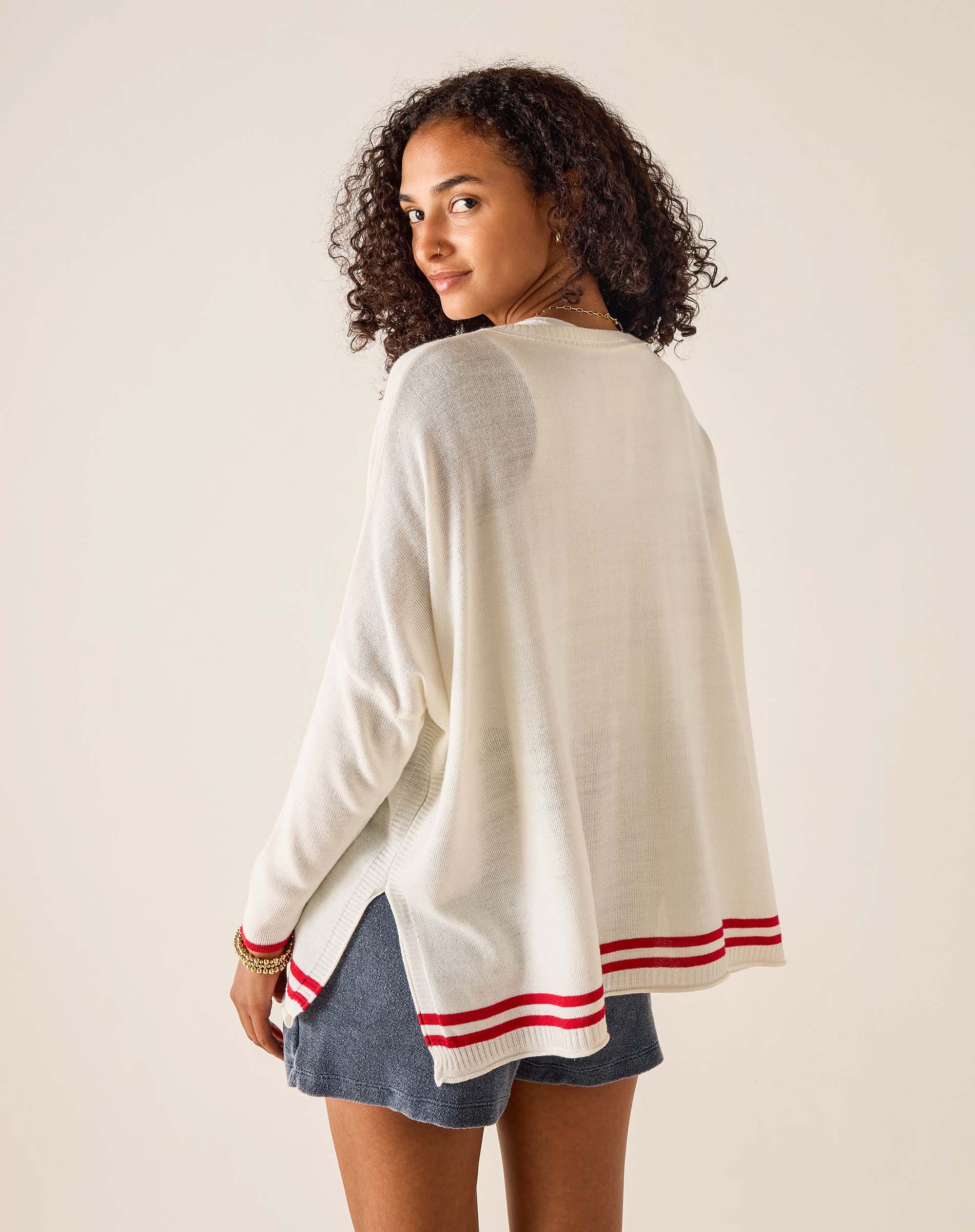 Woman wearing a white sweater with red stripes on a plain background