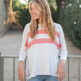 Woman wearing a white sweater with pink stripes outdoors