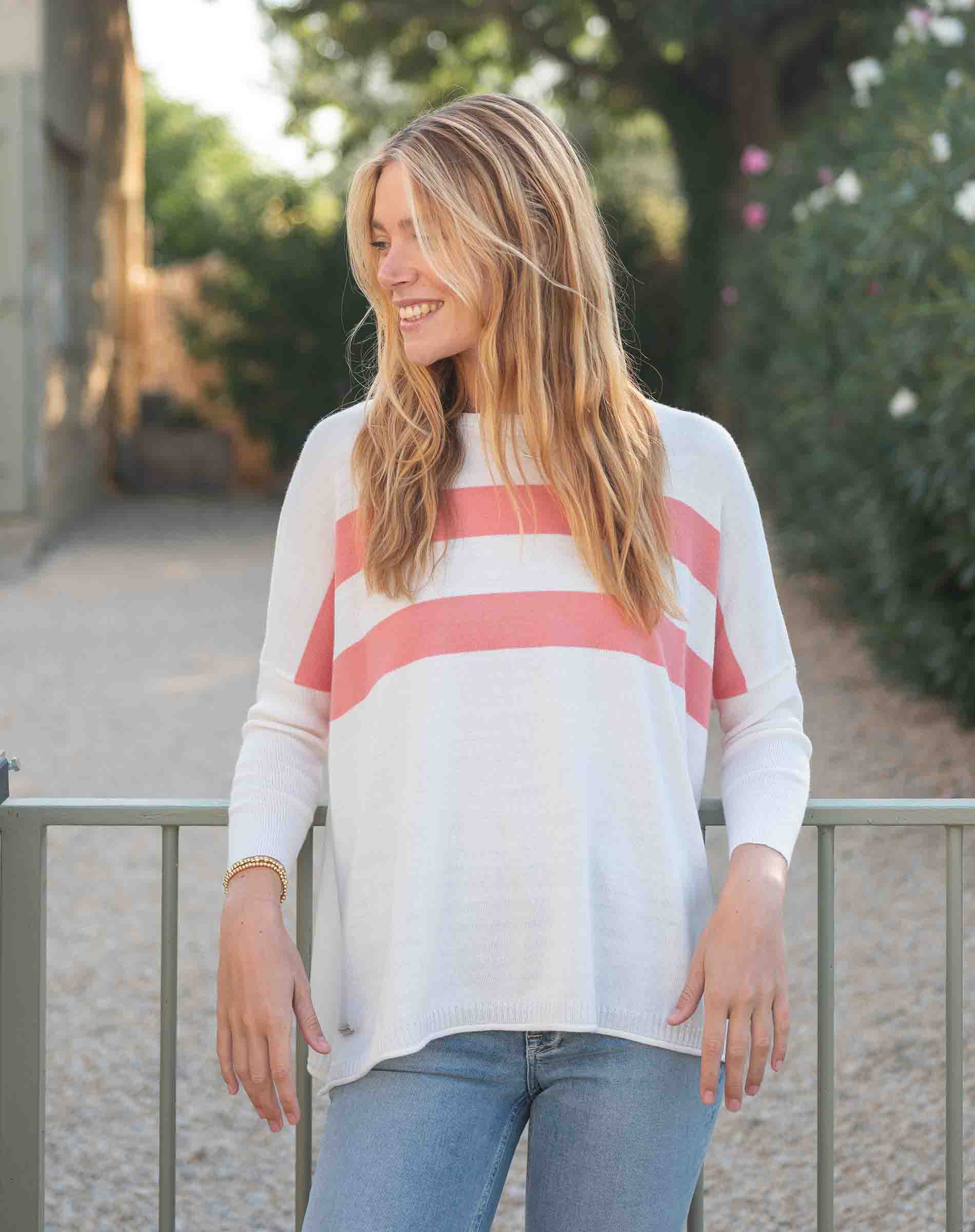 Woman wearing a white sweater with pink stripes outdoors