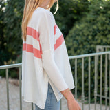 Person wearing a white cardigan with red stripes outdoors
