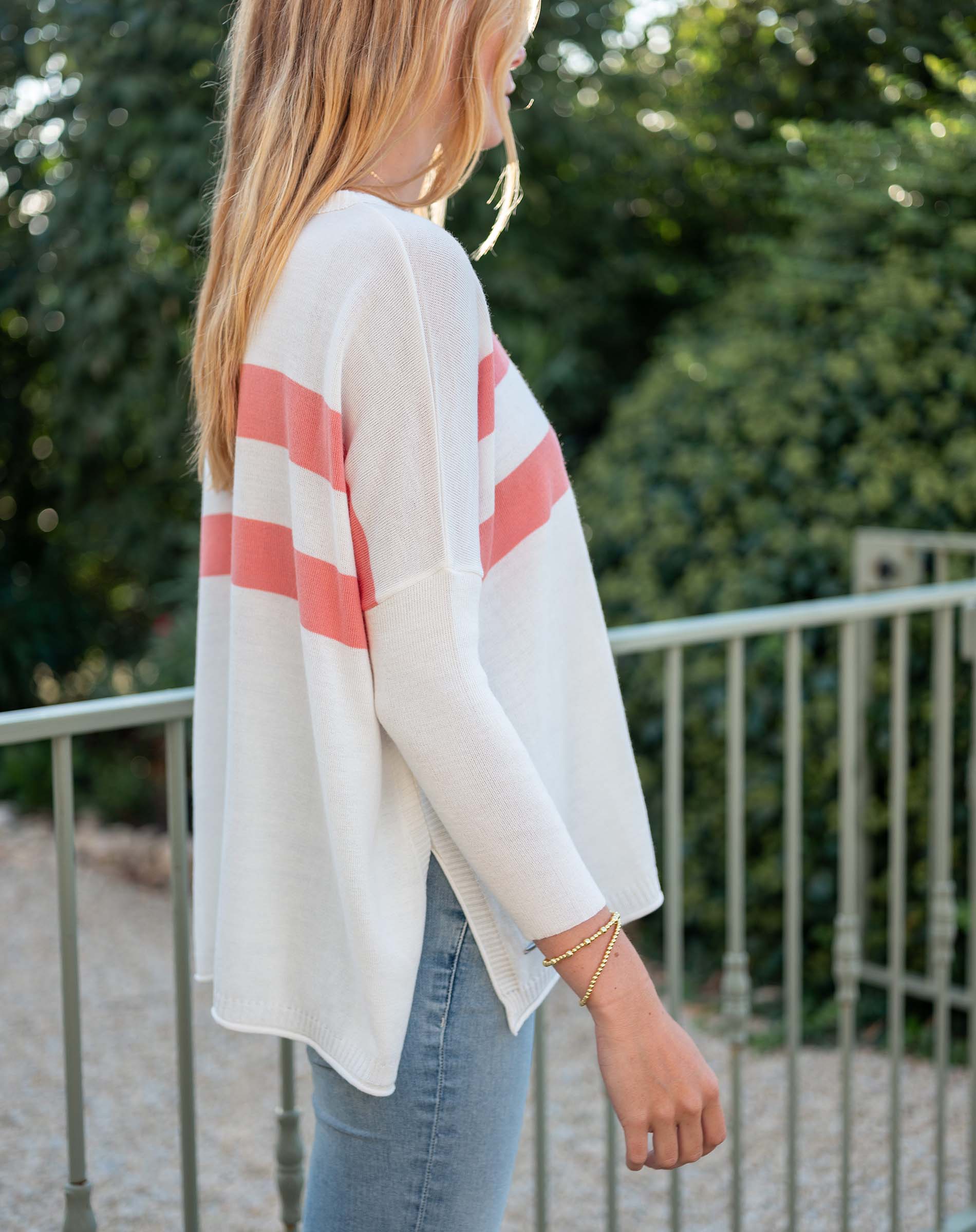 Person wearing a white cardigan with red stripes outdoors