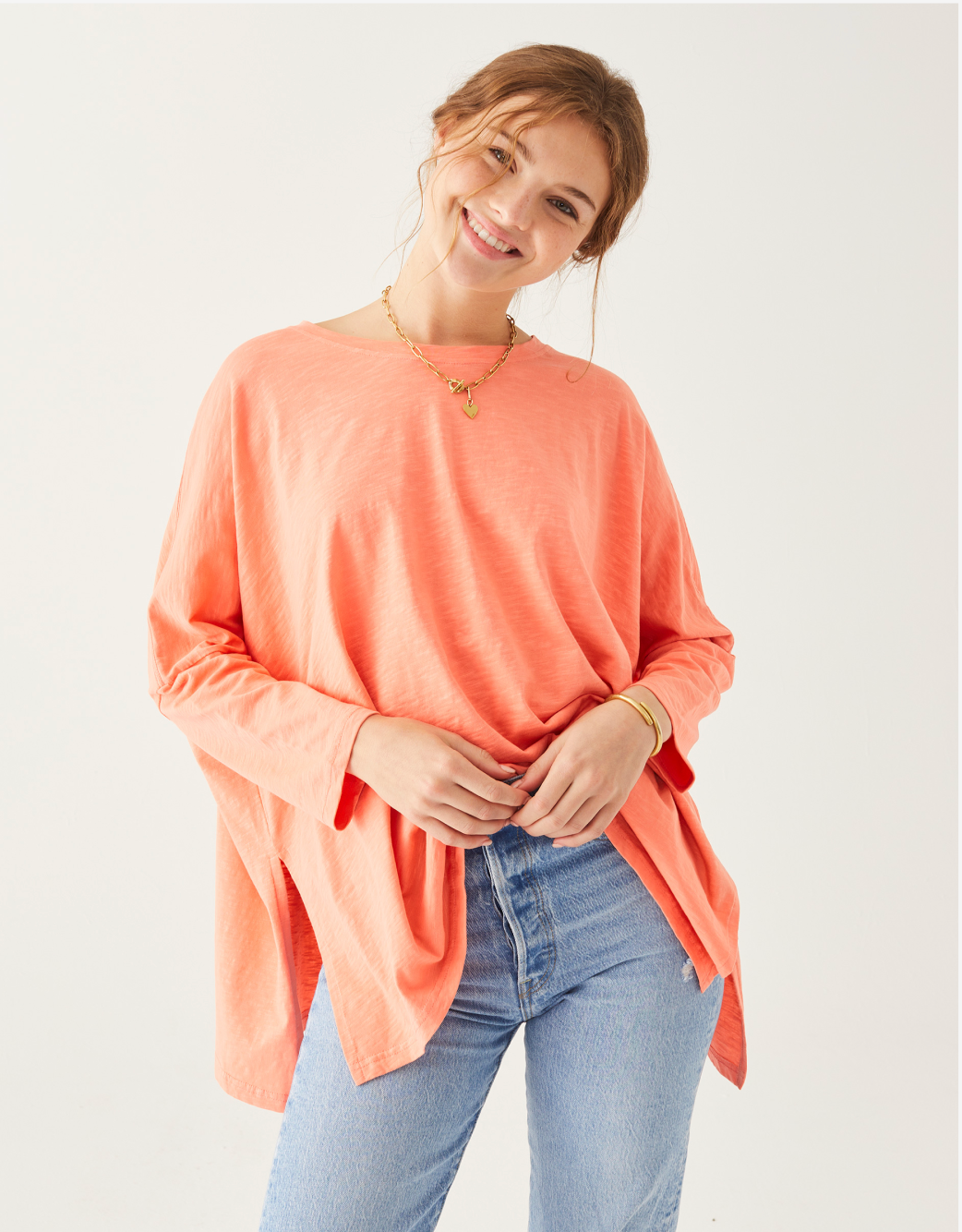 female wearing coral and pink tee shirt with long sleeves on a white background