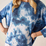 Person wearing a blue and white tie-dye shirt against a neutral background