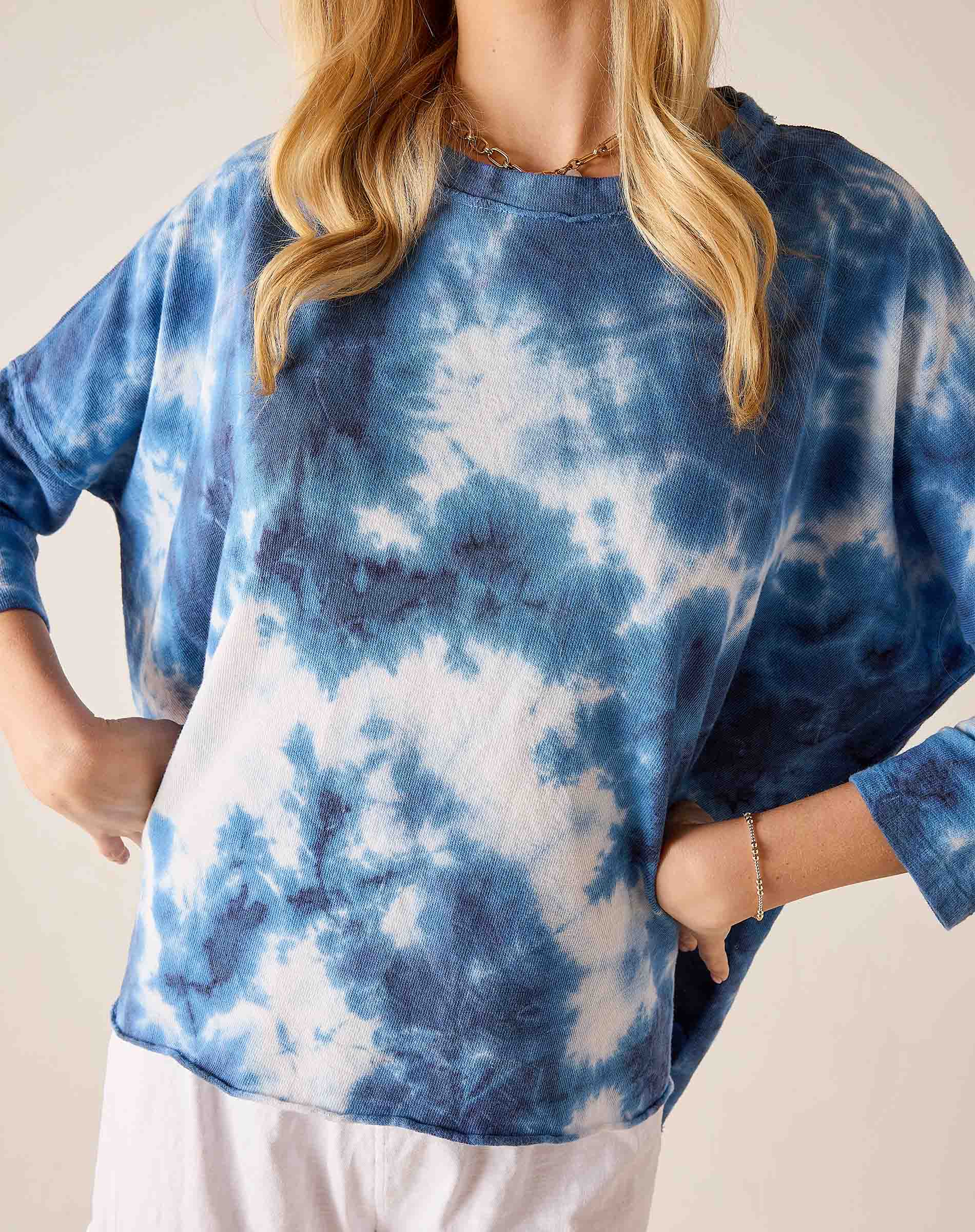 Person wearing a blue and white tie-dye shirt against a neutral background