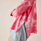 Person wearing a pink tie-dye shirt over a denim skirt on a plain background