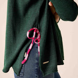 Forest green knit sweater with a pink and white striped tie-side detail and a small brand logo on the hem.