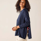 Woman wearing a navy cardigan over a white shirt with beige shorts on a plain background