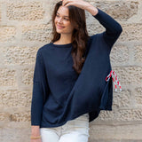 Woman wearing a navy blue sweater with a stone wall background