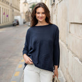 Woman wearing a navy blue sweater and light-colored pants standing on a street.