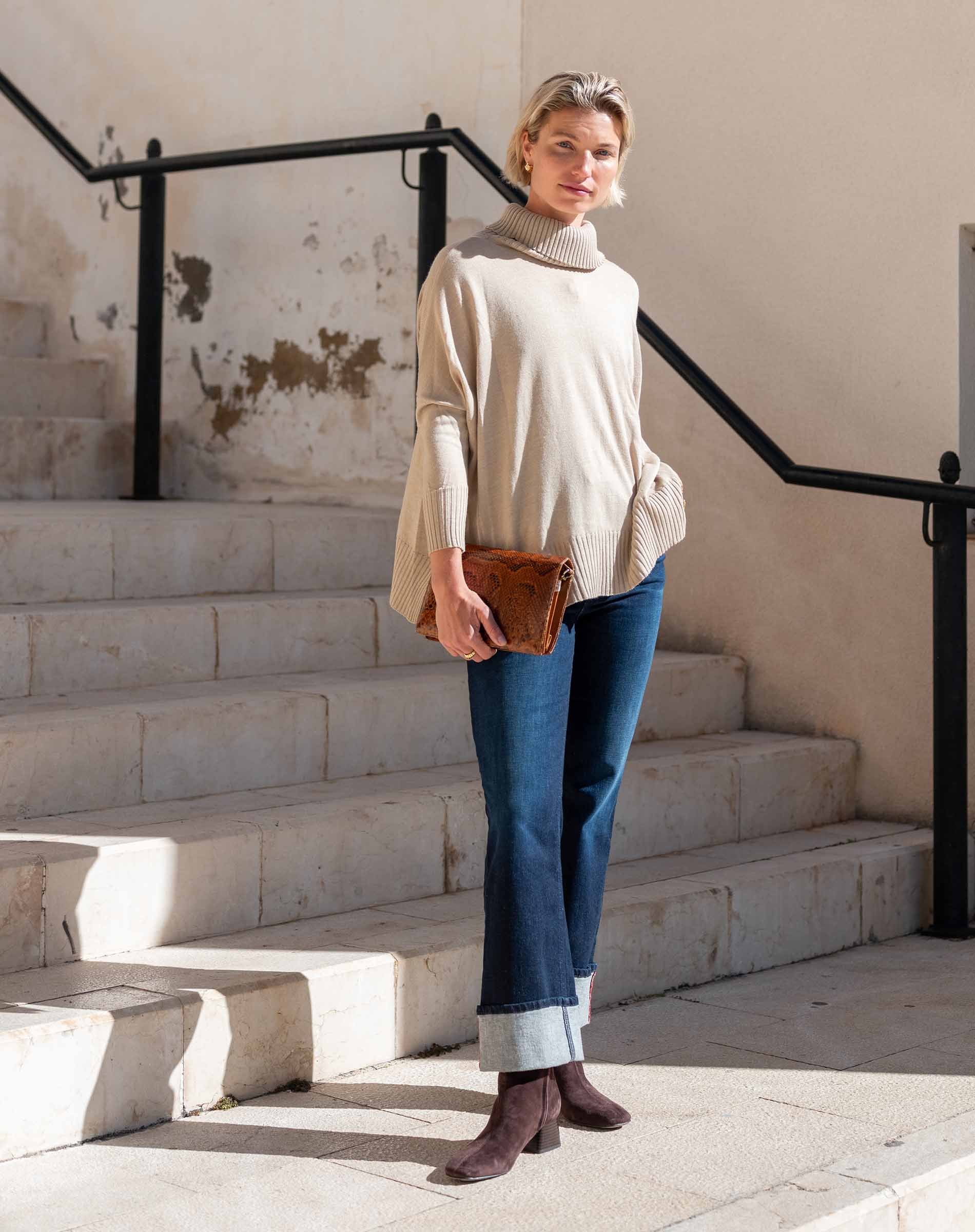 Putty-colored oversized turtleneck knit sweater with voluminous sleeves.