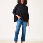 Woman wearing a black top and blue jeans against a white background