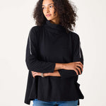 Woman wearing a black turtleneck sweater and blue jeans on a white background