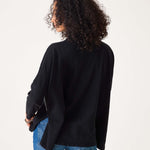 Person wearing a black cardigan and blue jeans on a white background