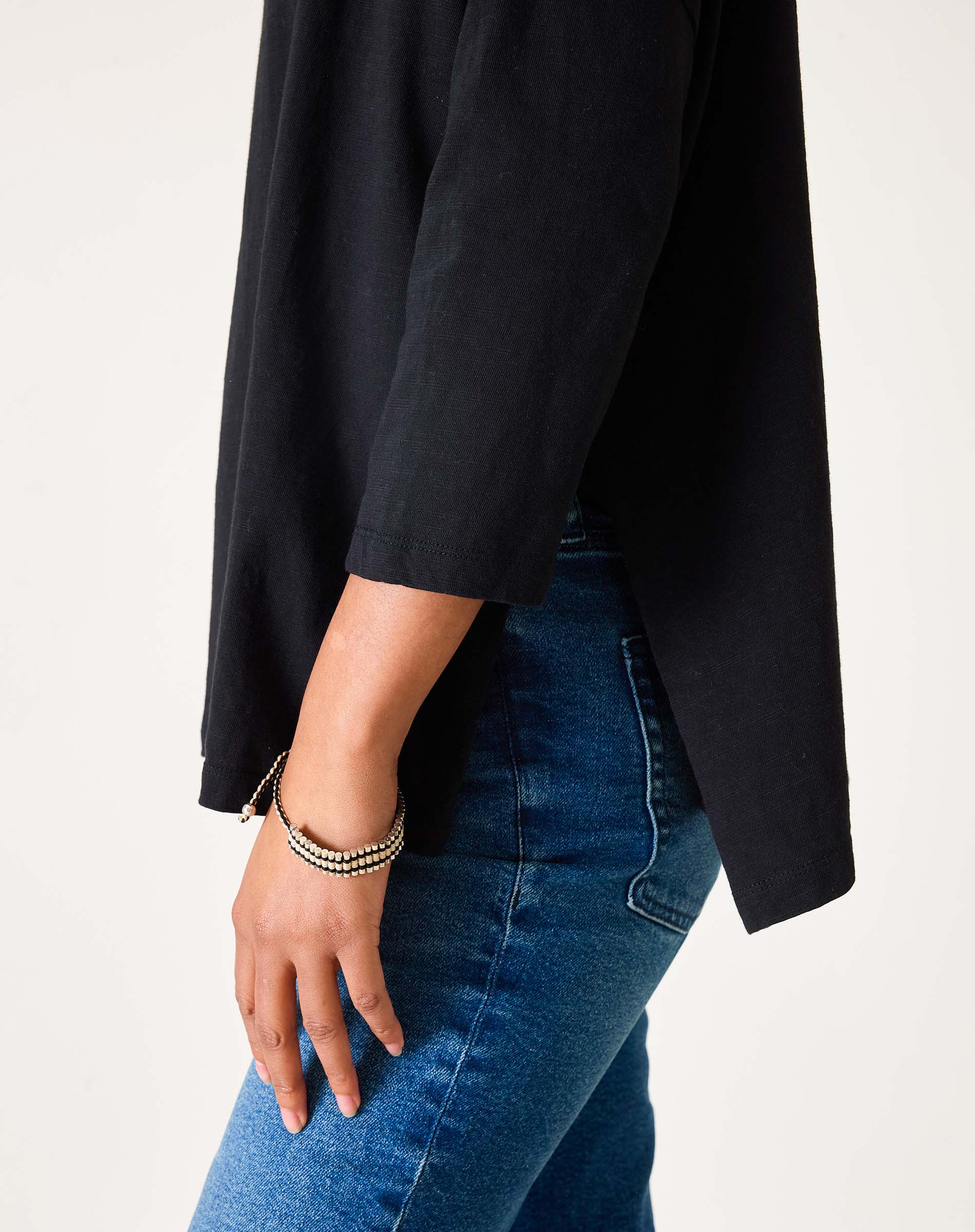 Person wearing a black jacket and blue jeans on a light gray background