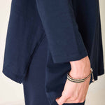 Person wearing a navy blue outfit with a beige background
