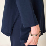 Person wearing a navy blue outfit with a beige background