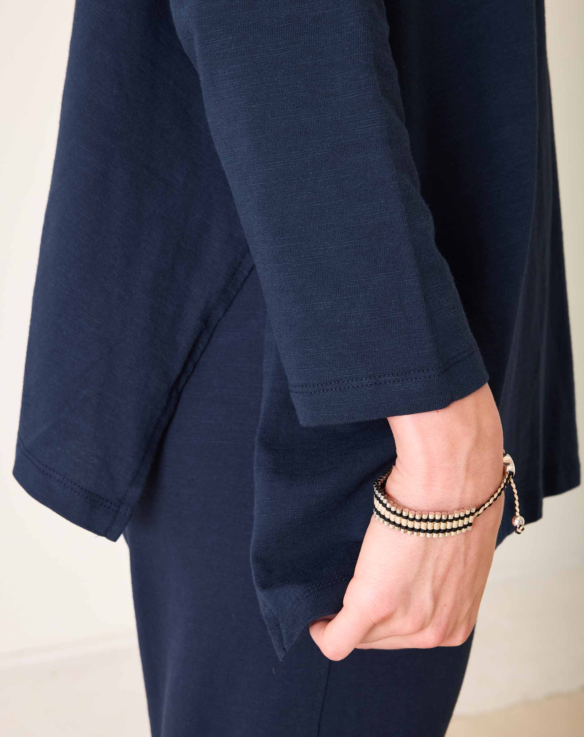 Person wearing a navy blue outfit with a beige background