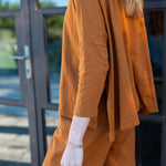 Person wearing a mustard yellow outfit standing in front of a glass door.