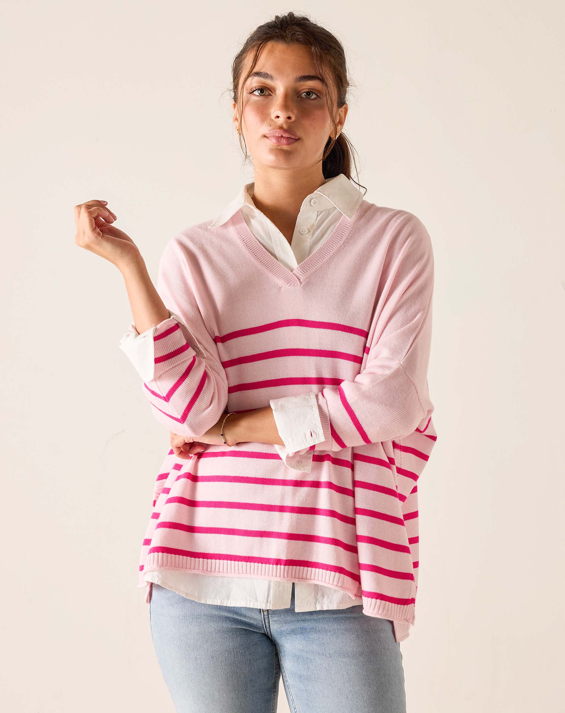 Woman wearing a pink and white striped sweater with a plain background