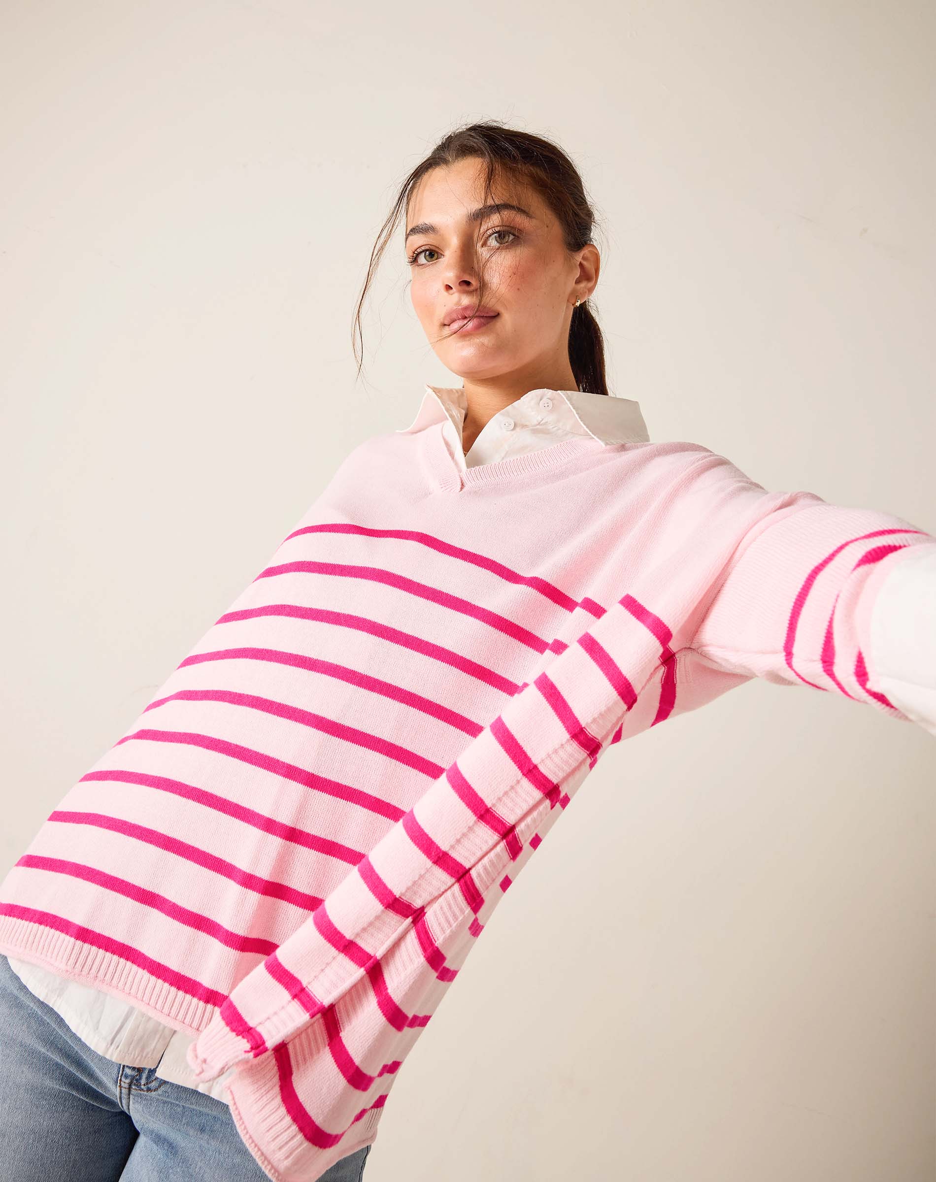 Woman wearing a pink and white striped sweater against a plain background