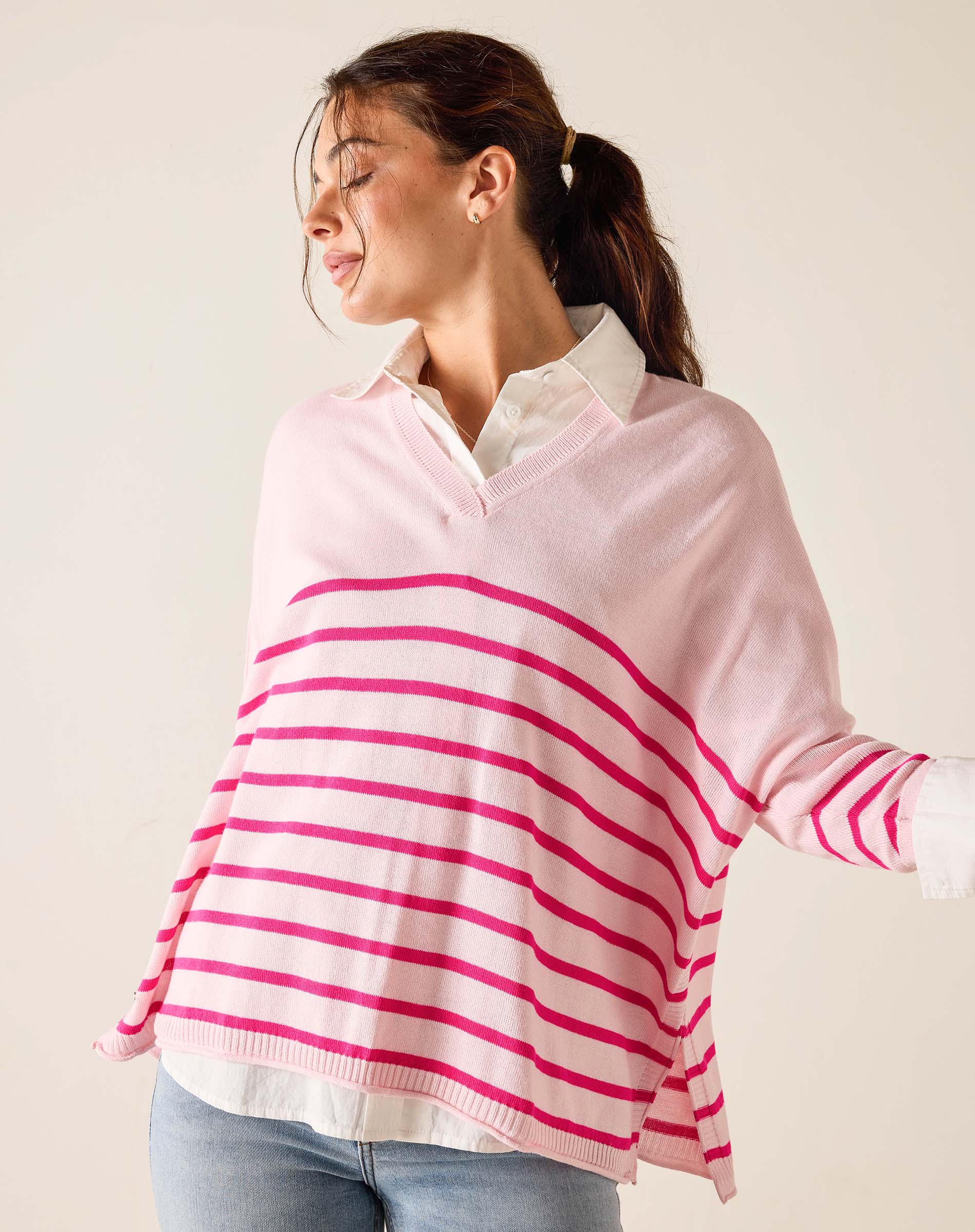 Woman wearing a pink and white striped sweater over a white shirt.