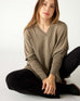 woman wearing mersea catalina v-neck sweater in hazelnut color sitting on floor