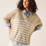 Woman wearing a beige and white striped sweater with a plain background