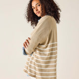 Woman wearing a beige cardigan over a striped shirt with a plain background