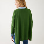 female wearing a green v neck sweater over a blue button shirt on white background