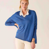 Woman wearing a blue sweater with a white collar against a light background