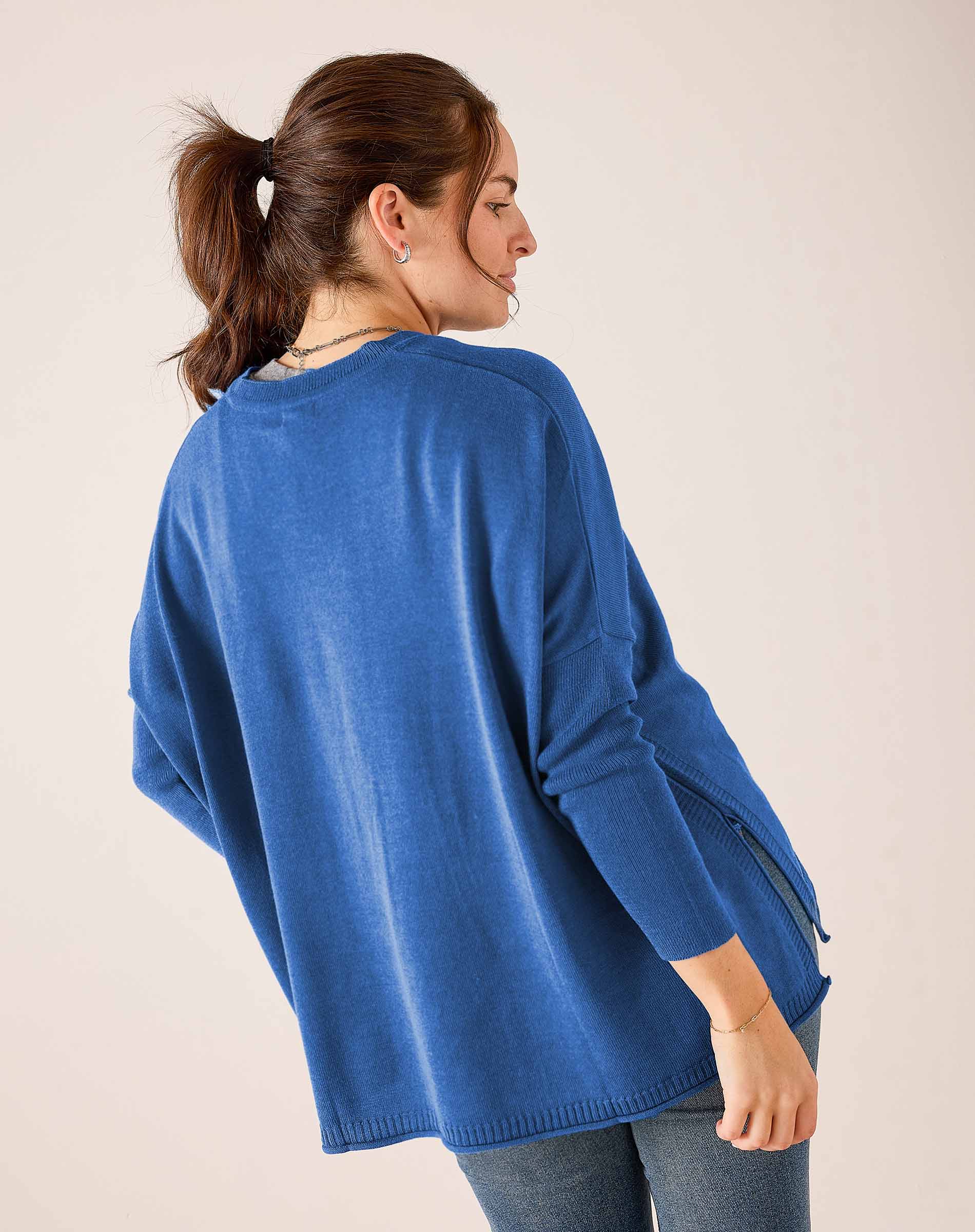 Side view of the ocean blue oversized knit V-neck sweater with ribbed hem and cuff details.