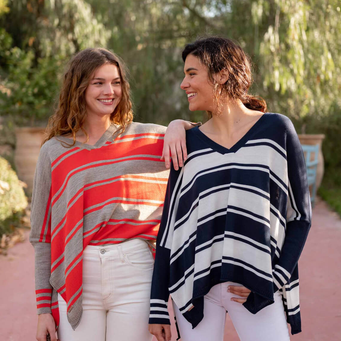 two females wearing striped v neck sweaters with split sides outside in spain