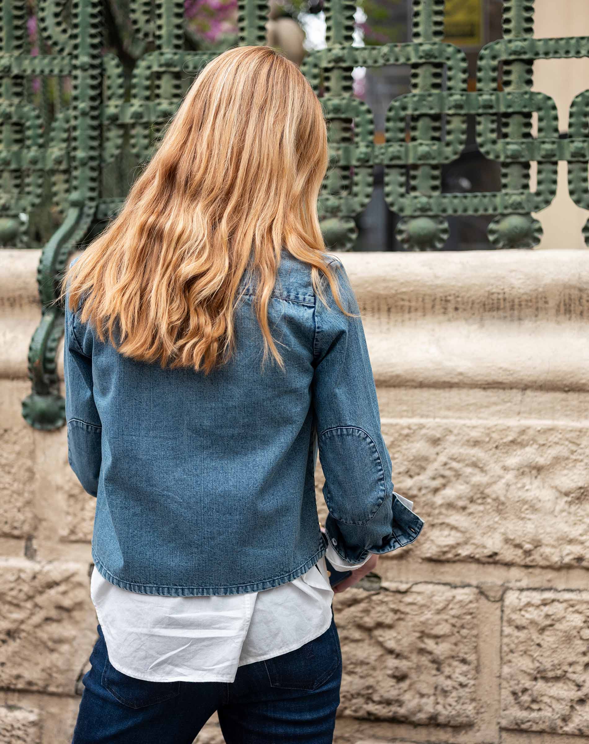 Back view of a woman wearing a women's travel-friendly stonewash chambray tuxedo shirt with wide sleeves