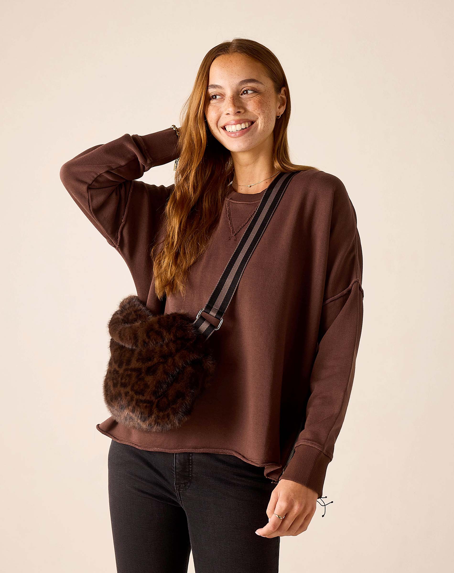 Chocolate brown faux fur crossbody bag with a wide striped strap.