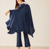 Woman wearing a navy blue poncho against a plain background