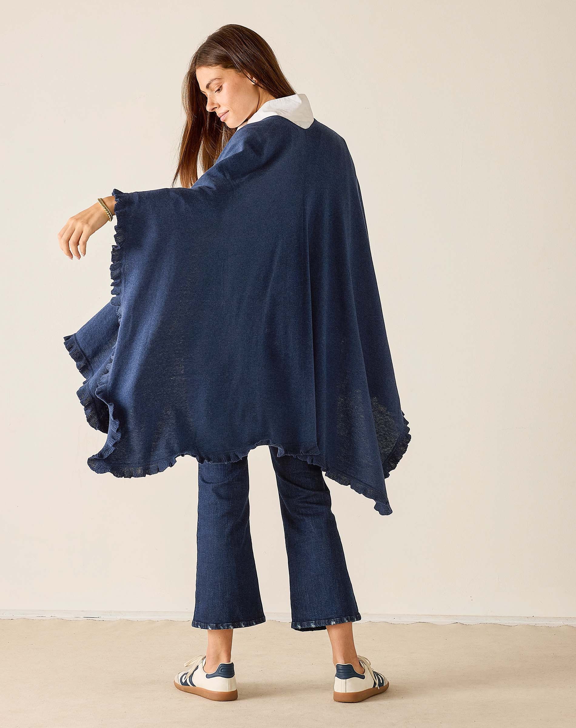 Woman wearing a navy blue poncho against a plain background