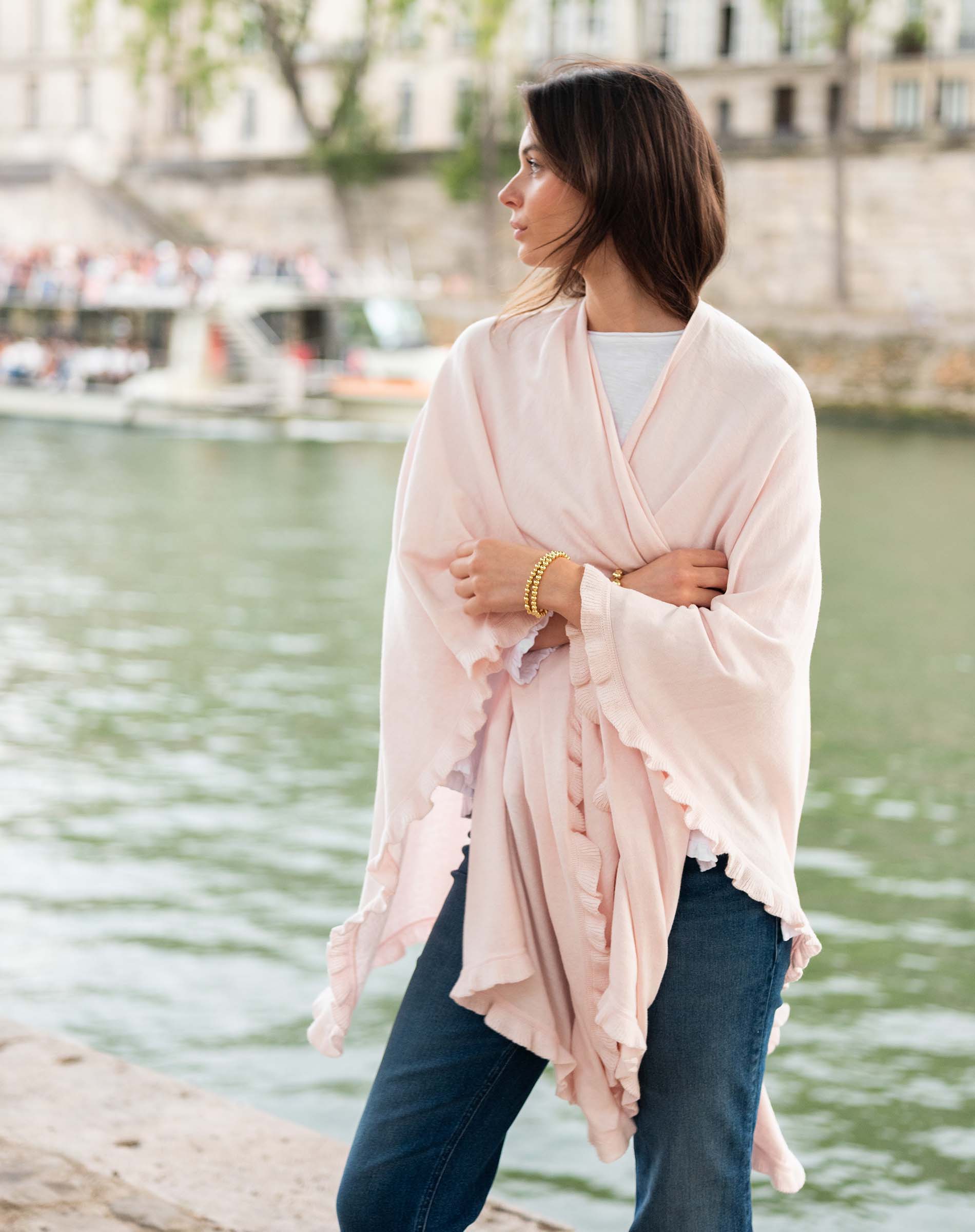 Woman wearing a light pink scarf by a waterfront with a blurred background